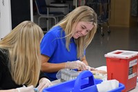 Students practicing with phlebotomy arm