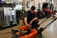 student working on lawn mower